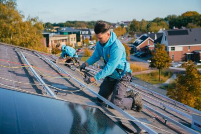 Zonnig monteur op het dak installeert een zonnepaneel.
